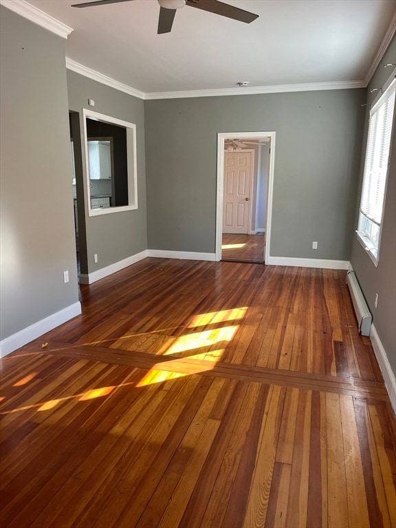 empty room featuring dark hardwood / wood-style floors, ceiling fan, crown molding, and a baseboard radiator