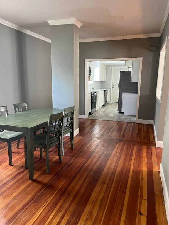 dining area with crown molding, sink, and light wood-type flooring