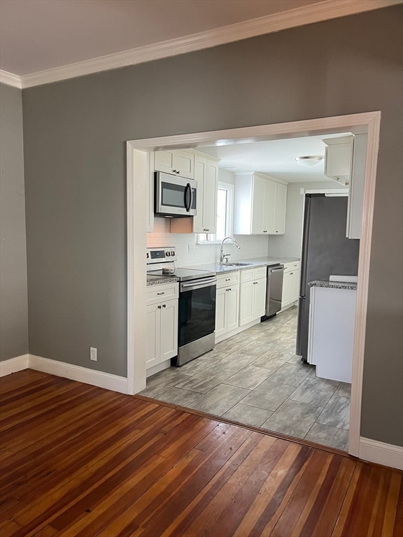 kitchen featuring white cabinets, crown molding, sink, appliances with stainless steel finishes, and light hardwood / wood-style floors