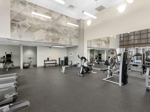 gym with a towering ceiling and a paneled ceiling