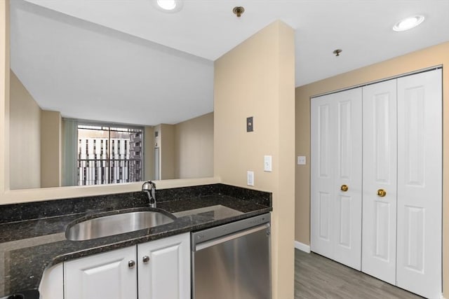 kitchen featuring wood-type flooring, sink, dark stone countertops, white cabinets, and stainless steel dishwasher