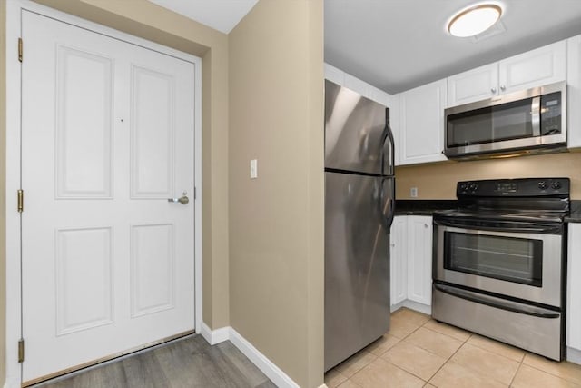 kitchen featuring stainless steel appliances, light tile patterned floors, and white cabinets