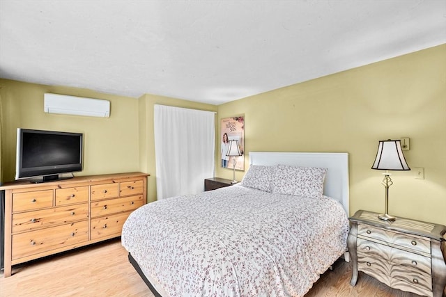 bedroom with light wood-type flooring and a wall mounted AC