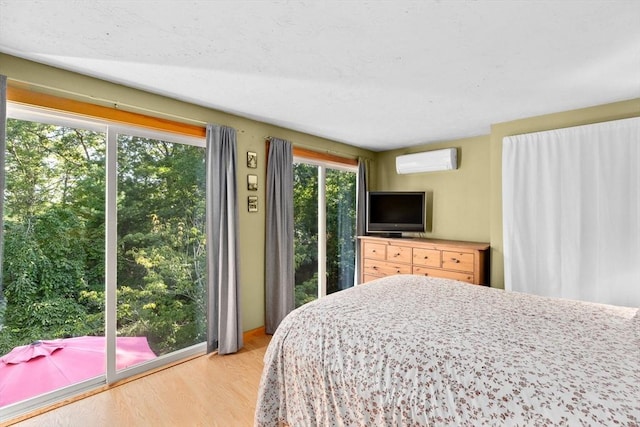 bedroom featuring access to exterior, light wood-type flooring, multiple windows, and a wall mounted AC