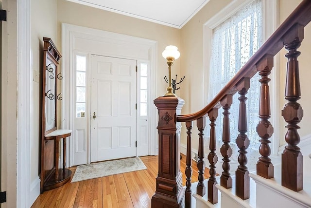 foyer entrance with stairway, light wood-type flooring, and ornamental molding