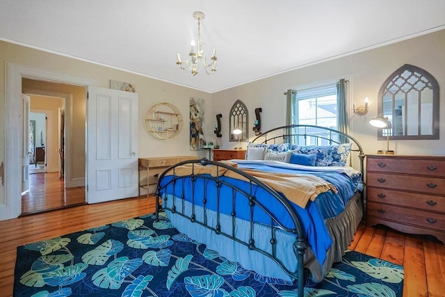 bedroom featuring hardwood / wood-style flooring, crown molding, and a chandelier