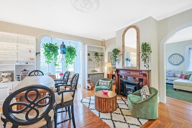 living area with built in features, crown molding, and wood finished floors