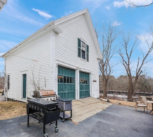 view of side of home featuring aphalt driveway and a patio area