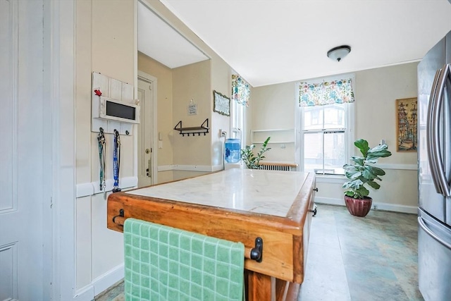 kitchen featuring a center island, light countertops, freestanding refrigerator, and baseboards