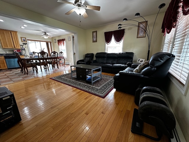 living room with light hardwood / wood-style floors, ceiling fan, and a wealth of natural light