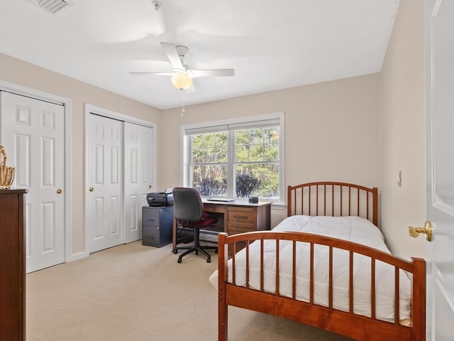 carpeted bedroom with multiple closets and ceiling fan