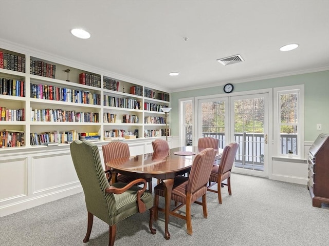 dining room featuring ornamental molding, light colored carpet, and built in features