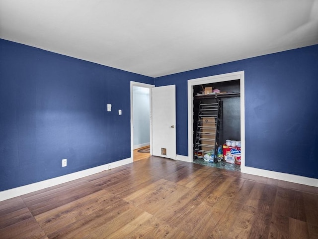 unfurnished bedroom featuring a closet, baseboards, and wood finished floors