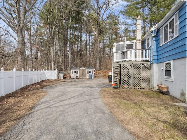 view of yard with an outbuilding, fence, driveway, a shed, and a deck