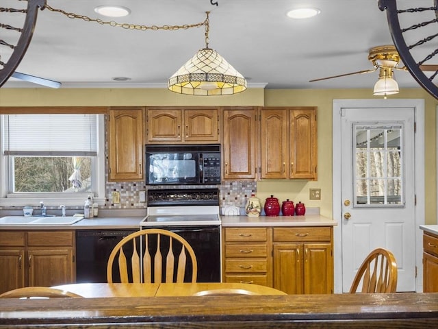 kitchen featuring backsplash, decorative light fixtures, light countertops, black appliances, and a sink