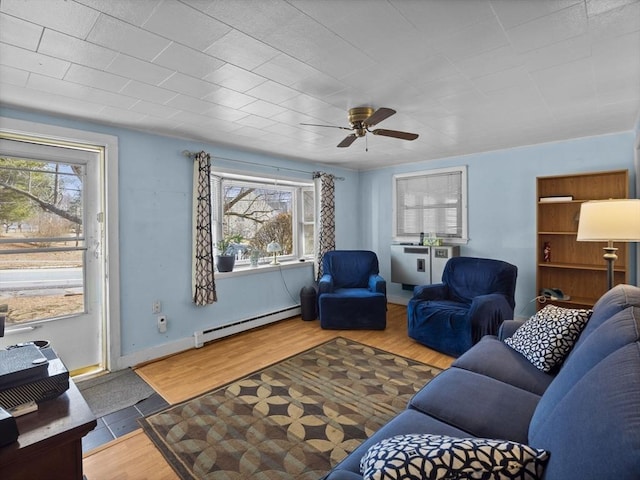 living area with a baseboard radiator, plenty of natural light, baseboards, and wood finished floors