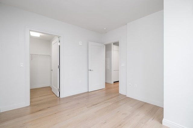 unfurnished bedroom featuring light hardwood / wood-style flooring, a walk in closet, and a closet