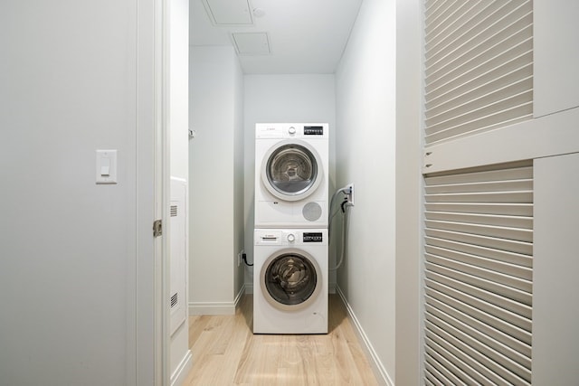 laundry area with light hardwood / wood-style flooring and stacked washing maching and dryer