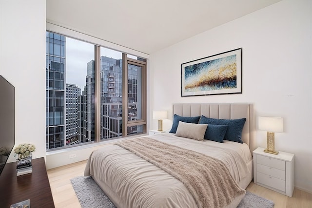 bedroom featuring a wall of windows and light wood-type flooring