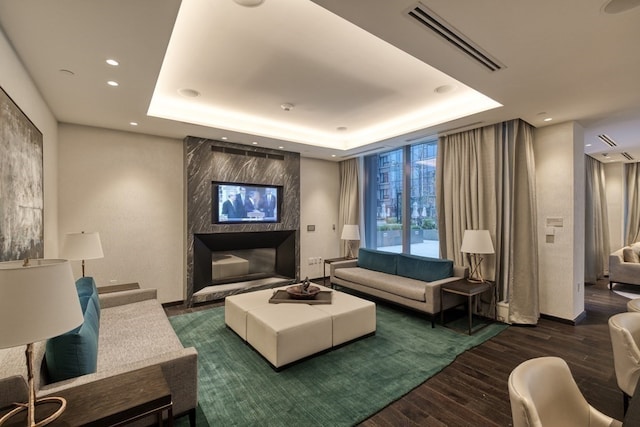 interior space with a multi sided fireplace, a raised ceiling, and dark hardwood / wood-style floors