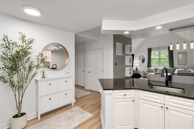 kitchen featuring a sink, open floor plan, light wood-style floors, white cabinetry, and recessed lighting