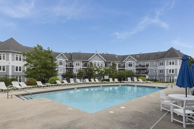 community pool featuring fence, a patio, and a residential view