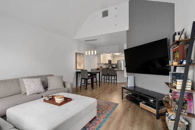 living area featuring high vaulted ceiling and light wood-style floors
