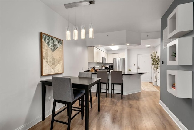dining room featuring light wood-style flooring and baseboards