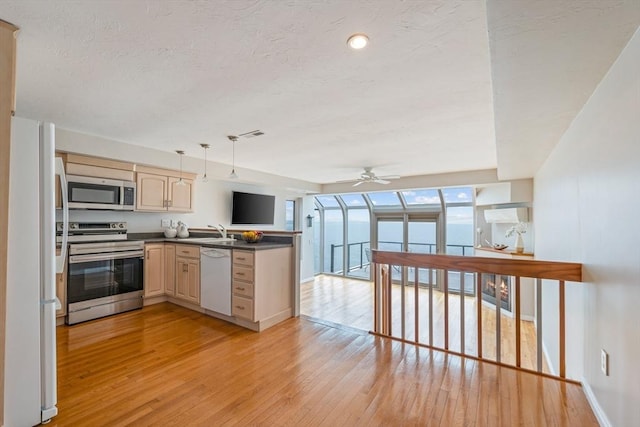 40 Oceanside Dr Unit 40, Hull, MA 02045 - kitchen featuring stainless steel appliances, light wood finished floors, ceiling fan, dark countertops, and cream cabinetry