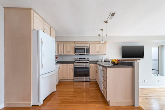 40 Oceanside Dr Unit 40, Hull, MA 02045 - kitchen with stainless steel appliances, dark countertops, light wood-type flooring, light brown cabinets, and a peninsula
