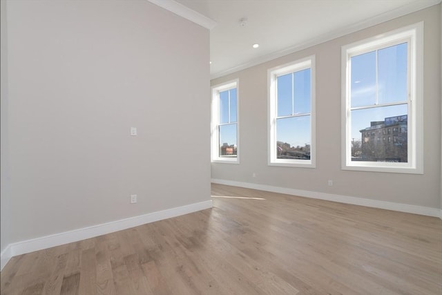 empty room featuring crown molding, light wood finished floors, recessed lighting, and baseboards