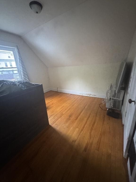 additional living space with lofted ceiling, hardwood / wood-style flooring, and baseboards