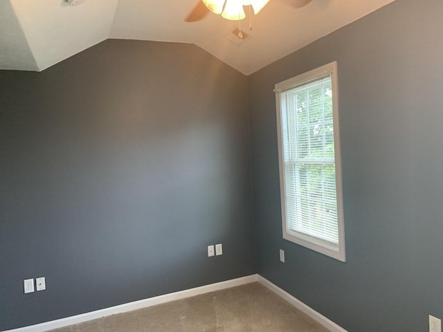 carpeted empty room featuring ceiling fan, lofted ceiling, and baseboards