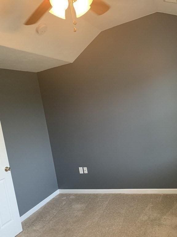 unfurnished room with ceiling fan, vaulted ceiling, light carpet, and baseboards