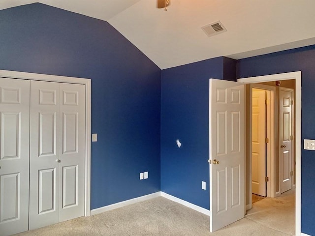 unfurnished bedroom featuring lofted ceiling, light carpet, a closet, baseboards, and a ceiling fan