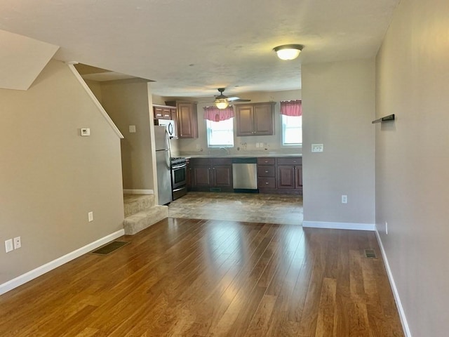 kitchen featuring appliances with stainless steel finishes, dark wood-style floors, baseboards, and a ceiling fan