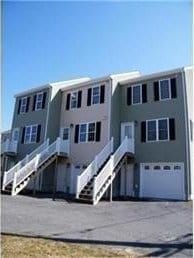 back of property featuring a garage, driveway, and stairs