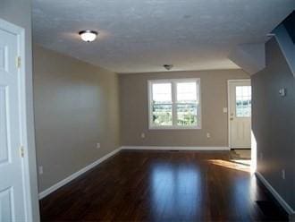 spare room with baseboards and wood finished floors