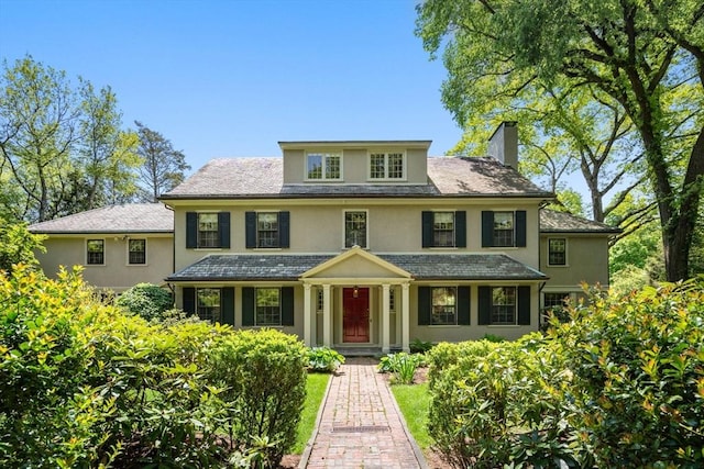 traditional style home with a chimney and stucco siding