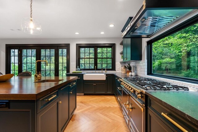 kitchen featuring wall chimney range hood, tasteful backsplash, stainless steel gas stovetop, and a sink