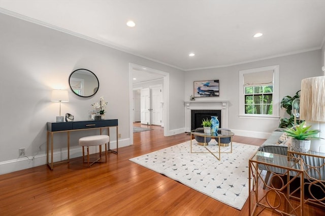 living area with recessed lighting, a fireplace, wood finished floors, baseboards, and crown molding