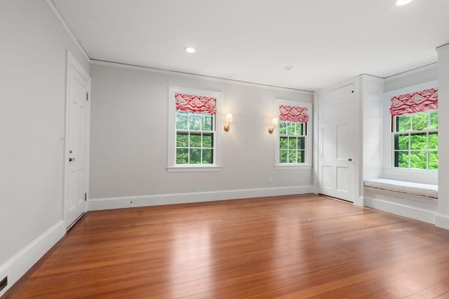 unfurnished room featuring crown molding, baseboards, and wood finished floors