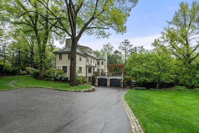 view of front facade featuring aphalt driveway, a front lawn, a wooden deck, and stucco siding