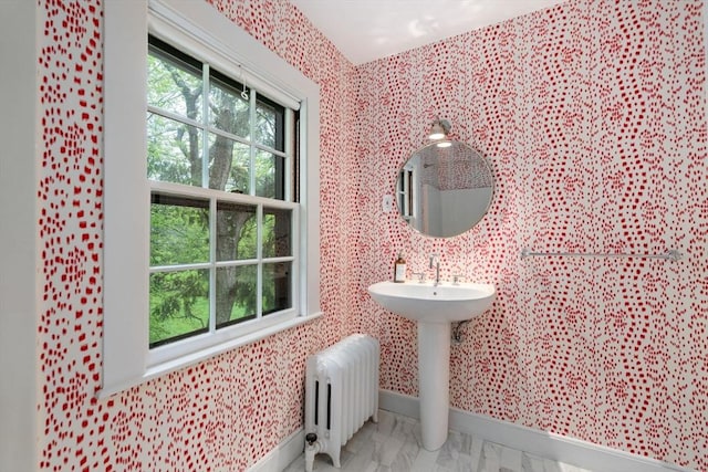 bathroom featuring radiator heating unit, baseboards, and a wealth of natural light