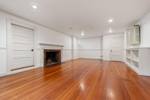 unfurnished living room featuring light wood finished floors, a brick fireplace, baseboards, and recessed lighting