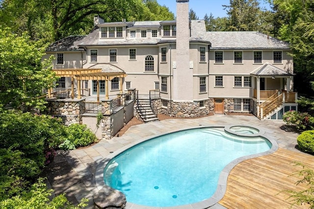 view of pool featuring a pool with connected hot tub, a pergola, a patio, and stairs