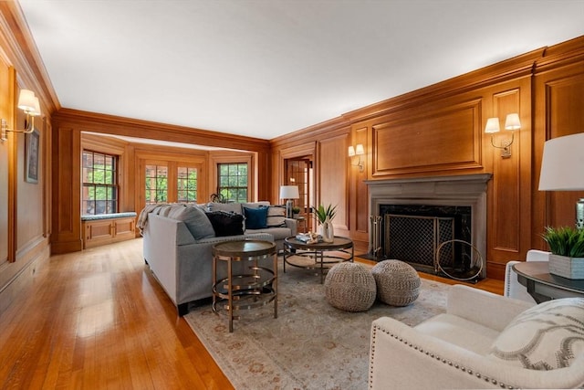 living area featuring ornamental molding, wood walls, a fireplace, and light wood-style flooring