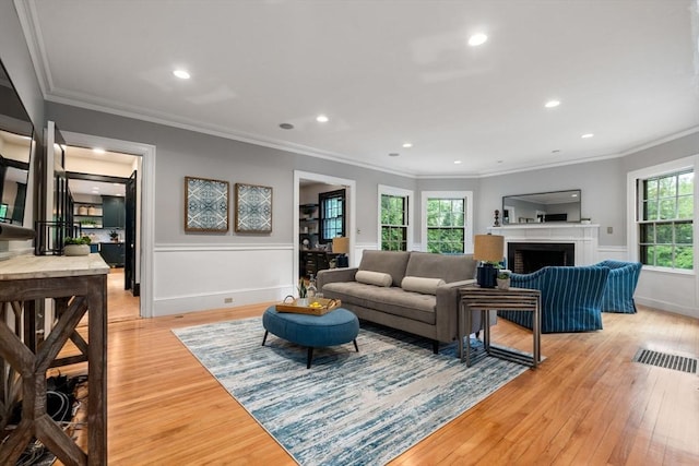 living room with ornamental molding, light wood-type flooring, a fireplace, and recessed lighting