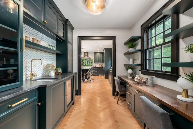 bar featuring backsplash, a sink, and built in study area