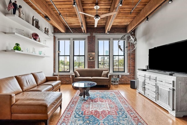 9 W Broadway Unit 311, Boston, MA 02127 - living area featuring rail lighting, brick wall, wooden ceiling with exposed beams, wood finished floors, and plenty of natural light
